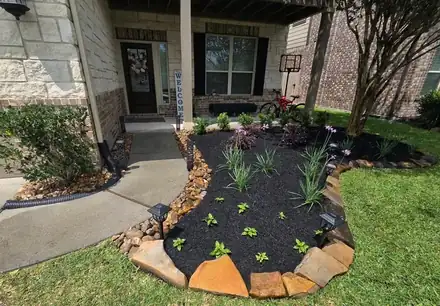 Flower bed with black mulch and a natural stone border (photo 1 of 8)