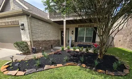 Flower bed with black mulch and a natural stone border
