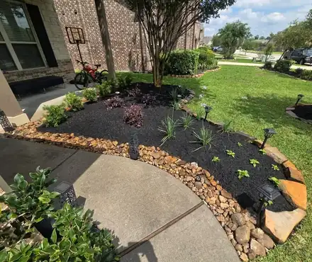 Flower bed with black mulch and a natural stone border (photo 7 of 8)