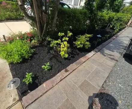 Stone walkway beside a mulched bed with a brick border