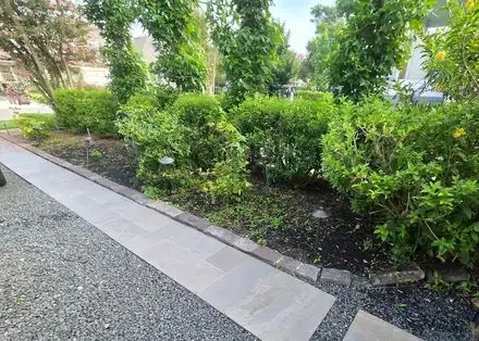 Stone walkway beside a mulched bed with a brick border (photo 6 of 8)
