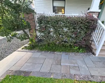 Stone walkway beside a mulched bed with a brick border (photo 7 of 8)